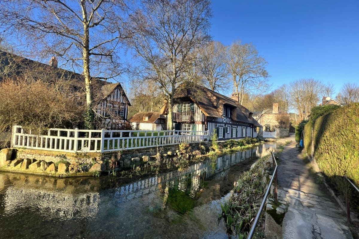 Vue pittoresque d'un village avec maisons traditionnelles et rivière ensoleillée.